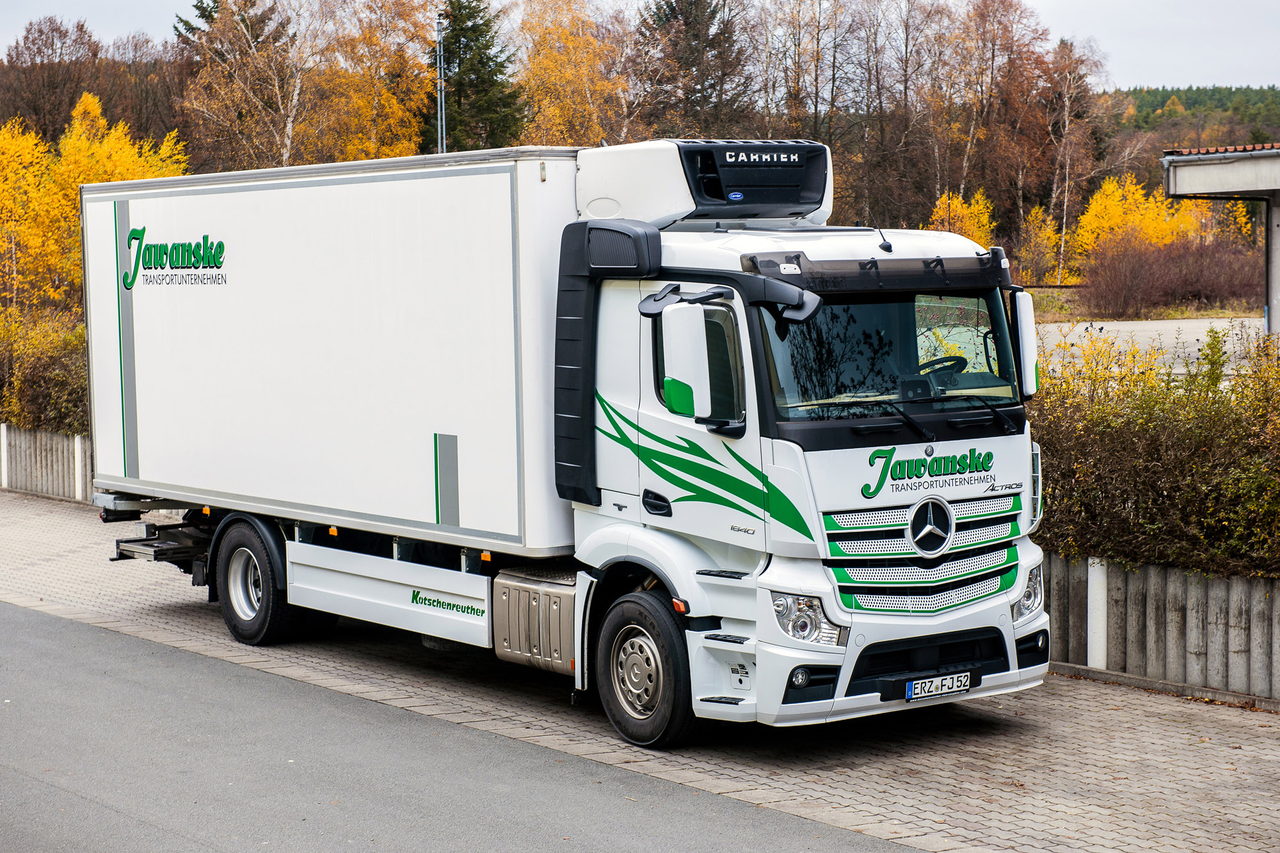 Weißer Mercedes-Benz Kühl-LKW mit grünem "Jüntschke" Logo auf der Seite parkt auf einer Straße.
